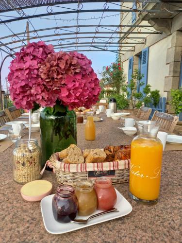 La Maison de Fleurat في Domeyrot: طاولة مع إناء من الزهور وصحن من الطعام