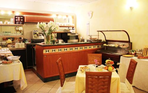 a restaurant with two tables and a counter with a kitchen at Albergo Al Viale in Trieste