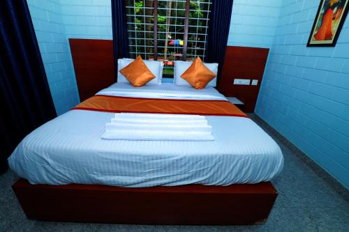 a bed with orange and white sheets and a window at NARMADA POOl VILLA in Angādipuram