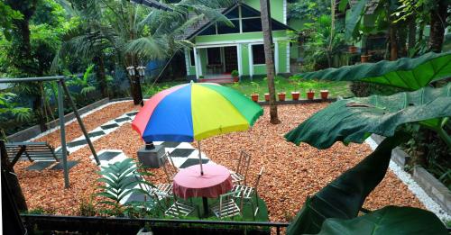 a colorful umbrella and two chairs and a table at NARMADA POOl VILLA in Angādipuram