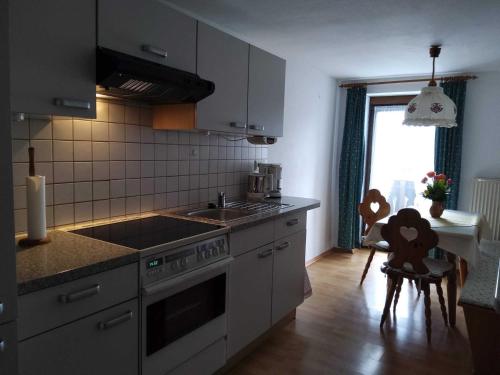eine Küche mit einem Herd, einem Waschbecken und einem Fenster in der Unterkunft Straßer-Hof in Teisendorf