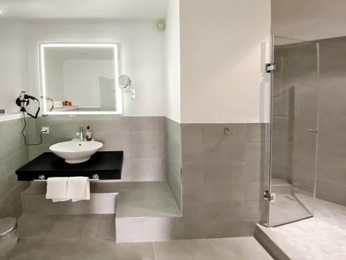 a bathroom with a sink and a shower at DORMERO Hotel Düsseldorf in Düsseldorf
