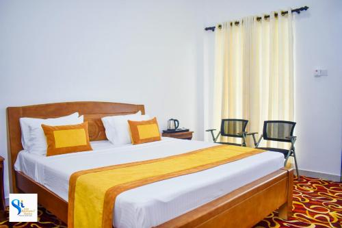 a bedroom with a large bed with yellow and white pillows at Hotel Summer Haven in Polonnaruwa