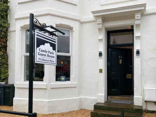 a sign in front of a building with a black door at Castle Park Guest House in Edinburgh