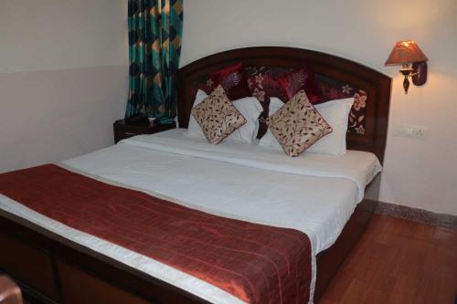 una camera da letto con un letto con lenzuola e cuscini bianchi di Hotel New Empire a Nuova Delhi