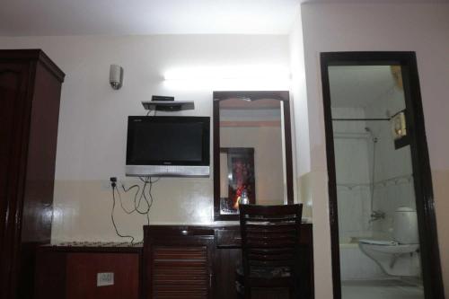 a bathroom with a tv on the wall and a mirror at Hotel New Empire in New Delhi