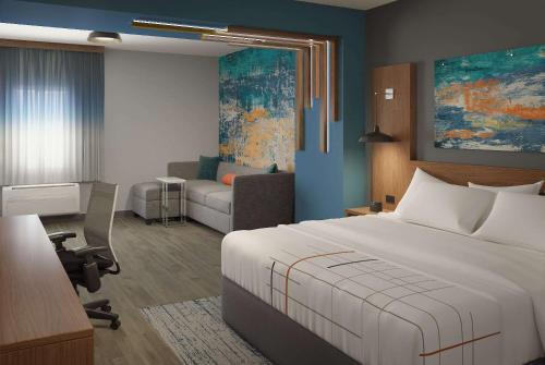 a hotel room with a bed and a living room at La Quinta Inn & Suites by Wyndham Bardstown in Bardstown