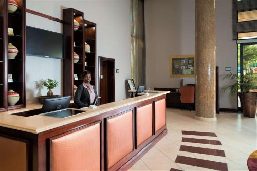 a woman standing at a reception desk in a lobby at The RidgePoint Hotel in Witbank