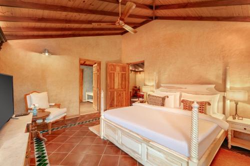 a bedroom with a large white bed in a room at Amritara Aura Resort & Spa in Mandrem