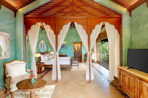 a bedroom with a bed and a tv in a room at Amritara Aura Resort & Spa in Mandrem