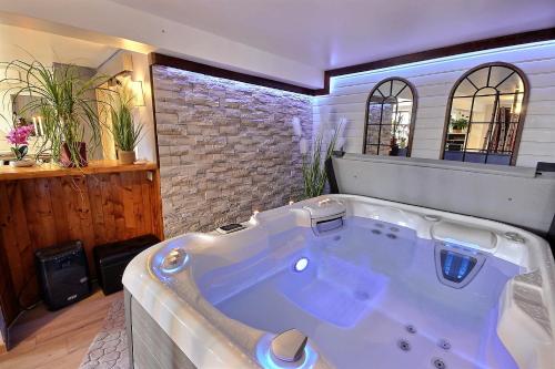 a large bath tub in a room with a brick wall at Spa et romance à Molliebon in Séez