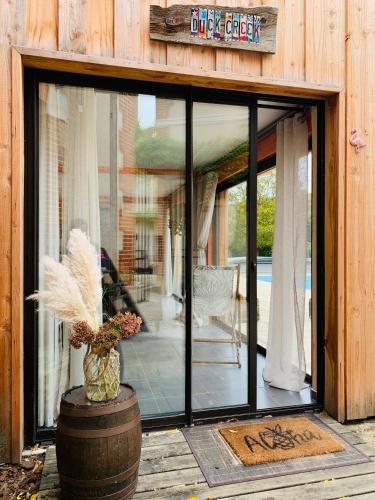 a sliding glass door of a house with a vase at Pool house-L'hirondelle de Sermizelles- grand jardin, calme et nature aux portes du Morvan in Sermizelles