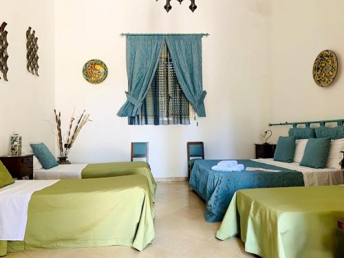 a room with three beds and a window at Agriturismo Carbona in Castelvetrano Selinunte