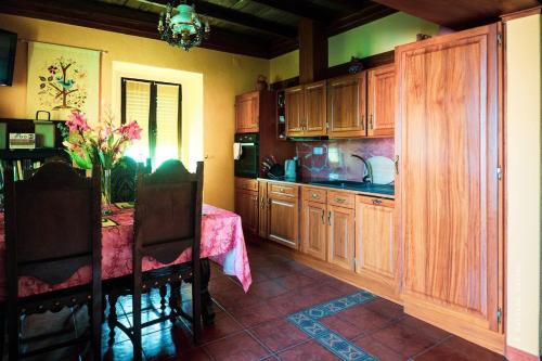 a kitchen with wooden cabinets and a table with a vase of flowers at Charming Garden Retreat in Pedrogao Grande in Pedrógão Grande