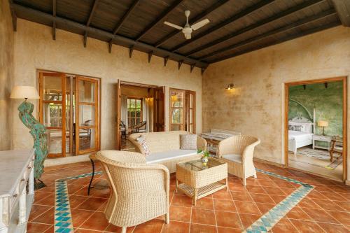 a living room with wicker chairs and a table at Amritara Aura Resort & Spa in Mandrem