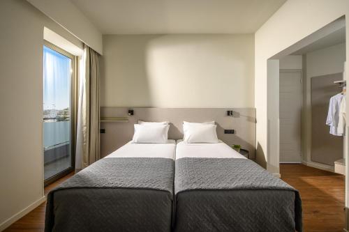 a bedroom with a large bed with a large window at Marin Hotel in Heraklio Town