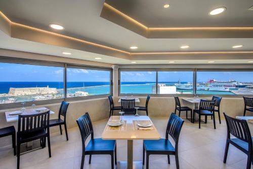 a restaurant with tables and chairs and a view of the ocean at Marin Hotel in Heraklio Town
