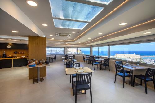 a restaurant with tables and chairs and a view of the ocean at Marin Hotel in Heraklio Town