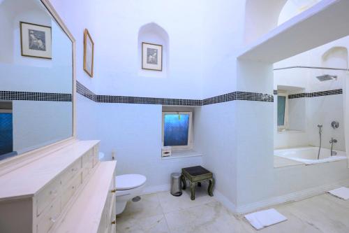 a white bathroom with a sink and a toilet at Neemrana Fort-Palace in Neemrana