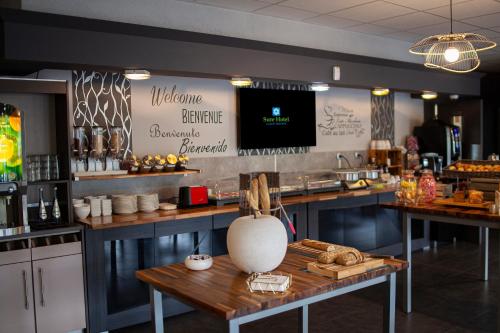 a coffee shop with a counter and a table with bread at Sure Hotel by Best Western Lille Tourcoing Ex Hotel Garden in Bondues