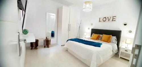 una camera bianca con un letto e un cartello che legge amore di Apartamento Orlando - Costa Adeje ad Adeje