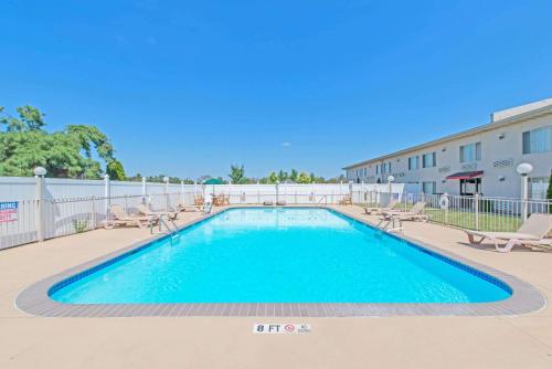 a swimming pool with chaises and chairs next to a building at Ramada by Wyndham Vineland Millville Area in Vineland