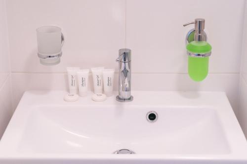 lavabo blanco con grifo verde en Gościniec Kasztel u Gostla, en Murowana Goślina