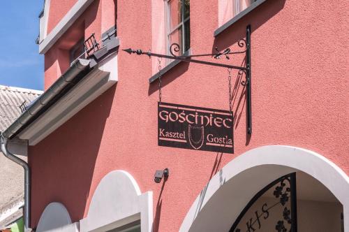 a pink building with a sign on the side of it at Gościniec Kasztel u Gostla in Murowana Goślina