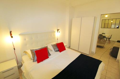 une chambre avec un grand lit blanc avec des oreillers rouges dans l'établissement Appartement confortable à Cannes avec climatisation - 53 m², à Cannes