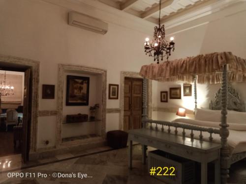 a bedroom with a bed and a chandelier at The Rajbari Bawali in Kolkata