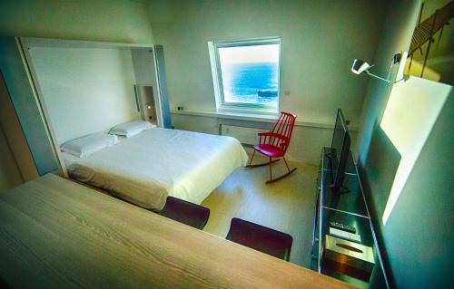 - une chambre avec un lit, une fenêtre et une chaise dans l'établissement Les Echappées Belles - Studio du phare, à Biarritz