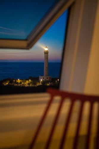 a view of a lighthouse from a window with a bench at Les Echappées Belles - Studio du phare in Biarritz