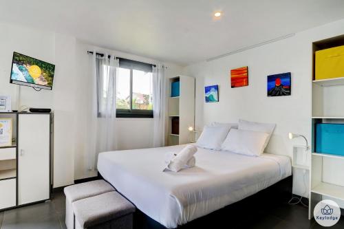a bedroom with a large white bed and a window at Les Gites Le Bambou - 3 étoiles - Les Avirons in Les Avirons
