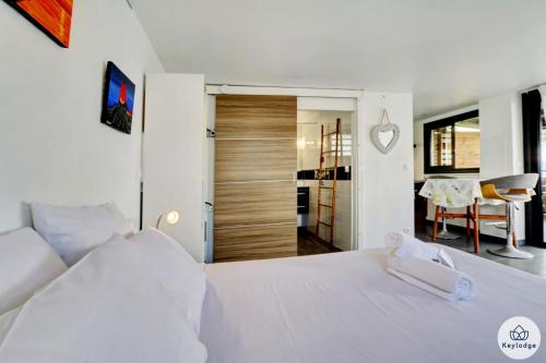 a bedroom with a white bed and a dining room at Les Gites Le Bambou - 3 étoiles - Les Avirons in Les Avirons