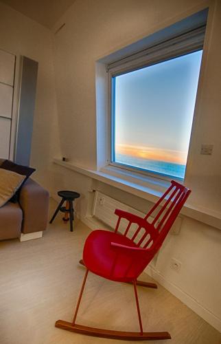 une chaise rouge assise dans une pièce avec fenêtre dans l'établissement Les Echappées Belles - Studio du phare, à Biarritz