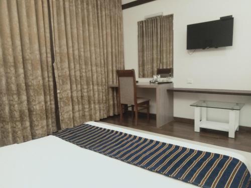 a hotel room with a bed and a desk and a television at Hotel Udayanraje Palace in Ahmadnagar