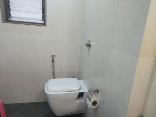 a white bathroom with a toilet and a window at Hotel Udayanraje Palace in Ahmadnagar