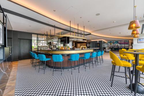 a restaurant with a bar with blue and yellow chairs at Mercure Neu-Isenburg in Neu Isenburg