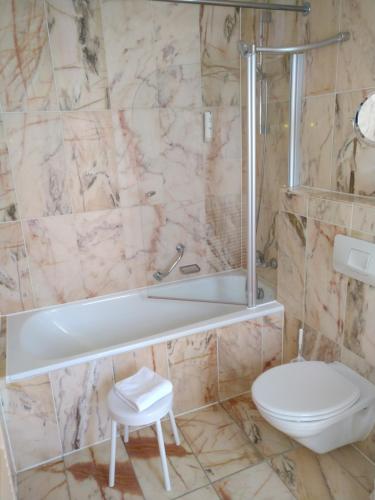 een badkamer met een wit bad en een toilet bij Landhotel Hirsch in Tübingen