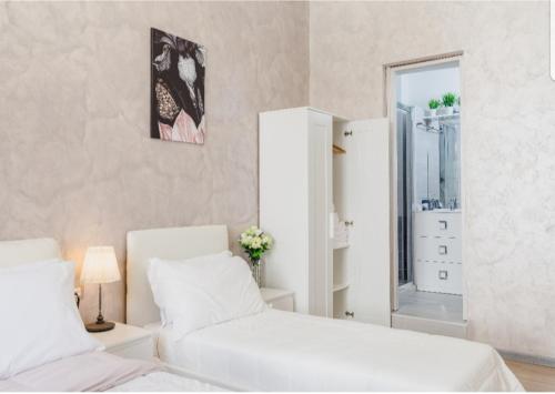 una camera da letto bianca con due letti e uno specchio di Rome Place a Roma
