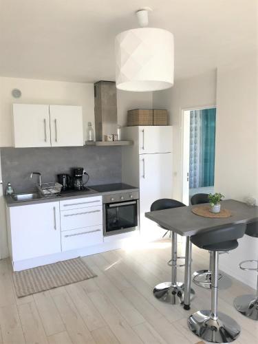 une cuisine avec des armoires blanches et une table avec des chaises dans l'établissement Cabourg - Bel appartement lumineux avec balcon dans résidence privée, à Cabourg