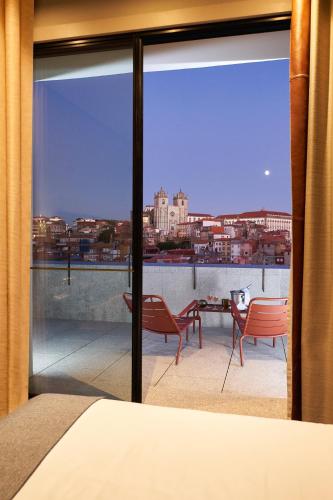 a bedroom with a view of the city from a balcony at PortoBay Flores in Porto
