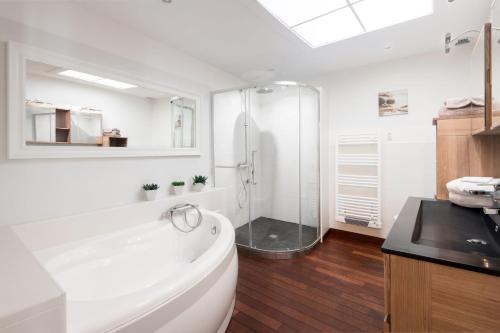 a white bathroom with a tub and a shower at LA SUITE GRANDE MAISON AU COEUR DU VILLAGE DE LA FLOTTE EN RÉ in La Flotte