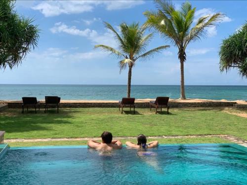 a man and a child in a swimming pool looking at the ocean at The Pleasure Kosgoda in Bentota