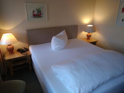 a bedroom with a large white bed with two lamps at Landhotel Hirsch in Tübingen