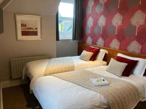 a hotel room with two beds and a window at The Bulls Head in Milnthorpe