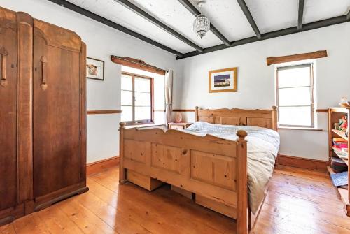 a bedroom with a wooden bed and windows at Idyllic Country Cottage - Dog Friendly, 6 mins drive to Saunton Beach- World Class Surfing Reserve! 5 mins drive to Golf Course, REDUCED RATES! in Braunton