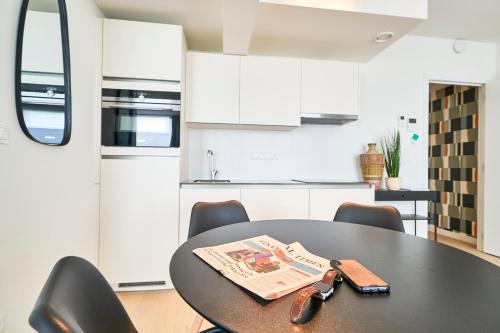 a kitchen with a table and chairs with a newspaper on it at Diamant Studio in Brussels
