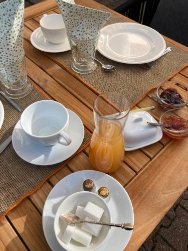 una mesa de madera con platos blancos y una taza de zumo de naranja en Le Clos Corbier - Champagne Collard-Milesi, en Mareuil-sur-Ay