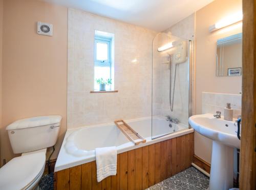 a bathroom with a tub and a toilet and a sink at Coeden Afal in Kidwelly